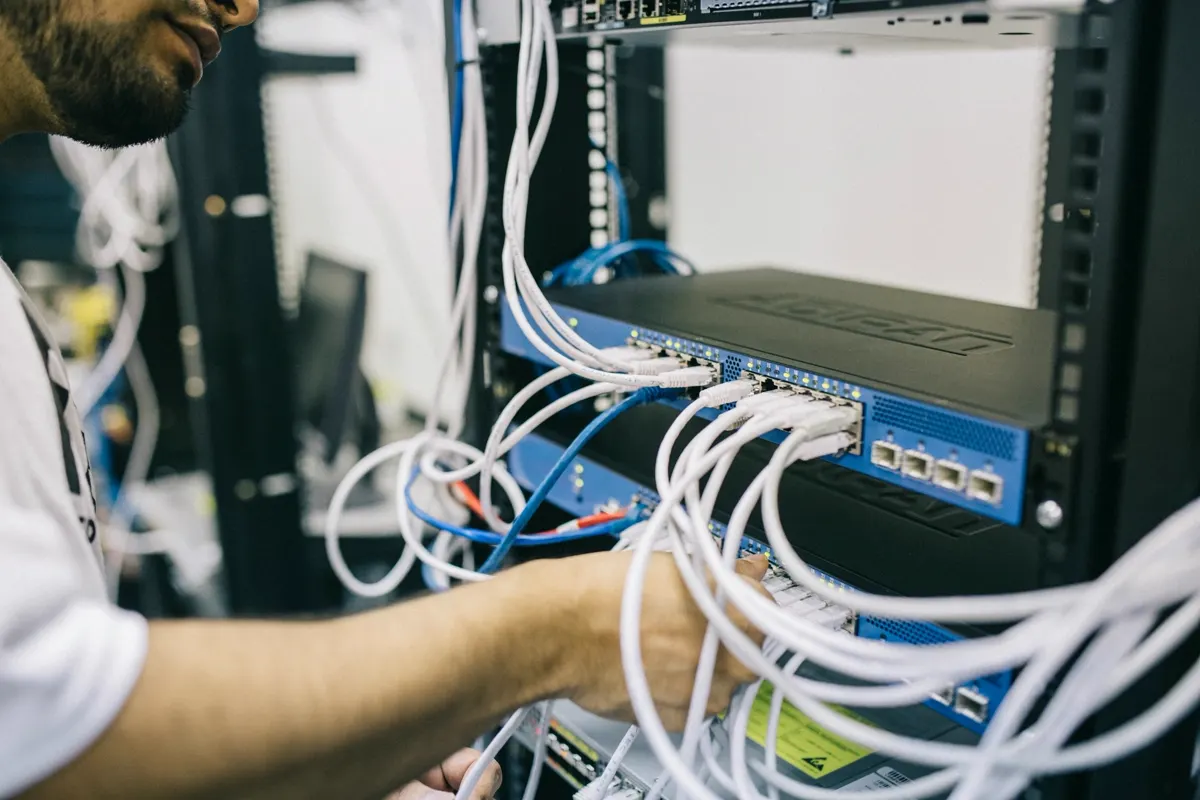 Técnico organizando cableado de red en un rack de comunicaciones